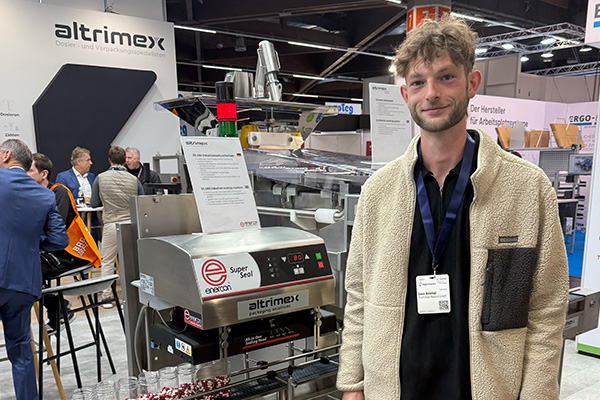 Person steht an einem Messestand vor einer Verpackungsmaschine